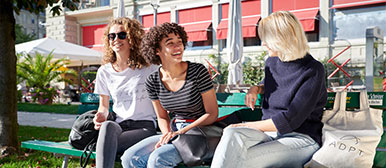 studierende vom hospitality management bachelor sitzen auf einer bank