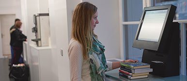 Frau leiht Bücher in Bibliothek aus