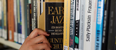 Jemand nimmt ein Buch aus einem Bücherregal