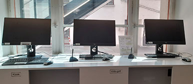 Drei Bildschirme auf einem langen Tisch