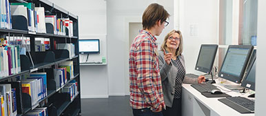 Zwei Personen vor zwei Bildschirmen